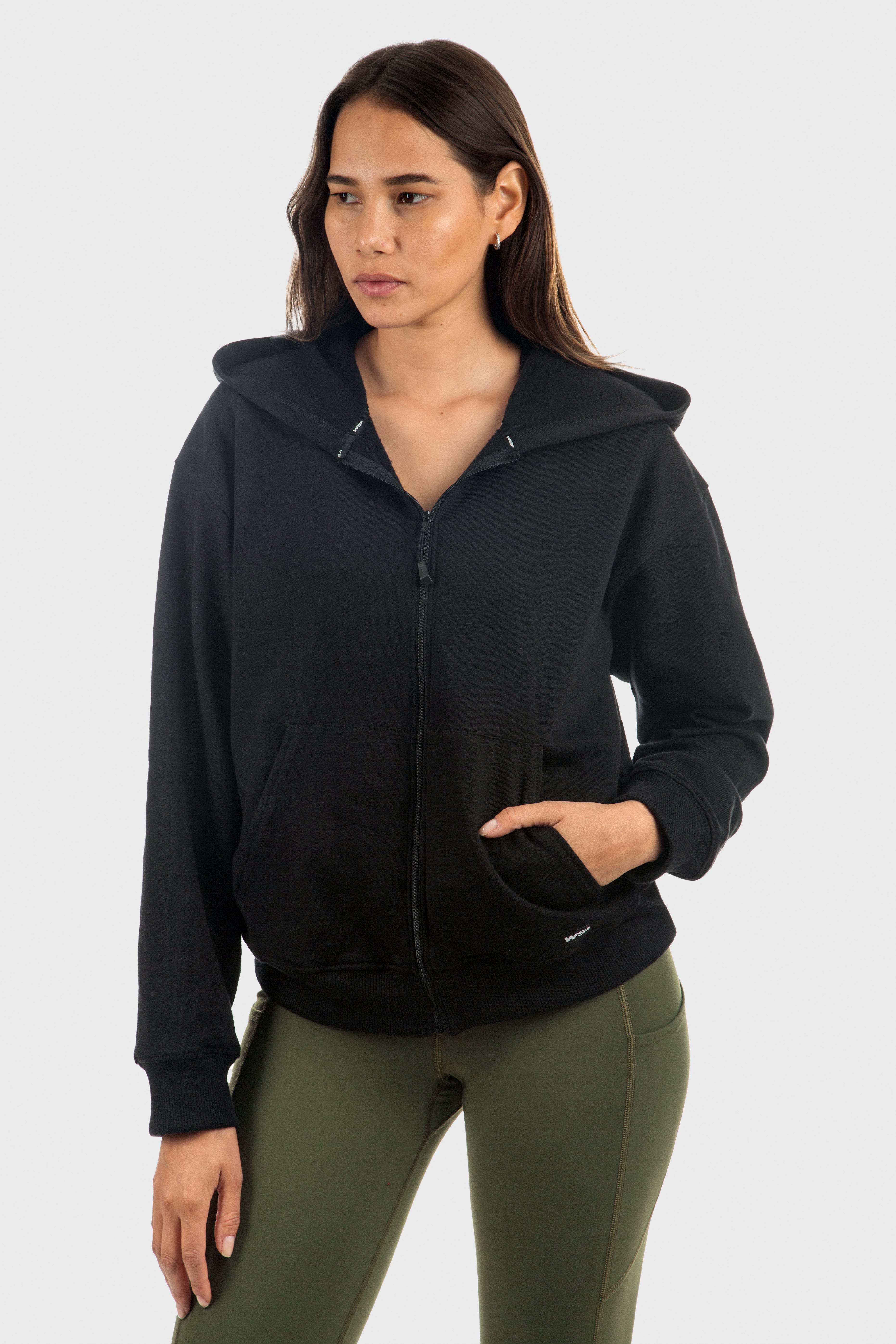 Woman wearing a black hoodie and green pants on a white background