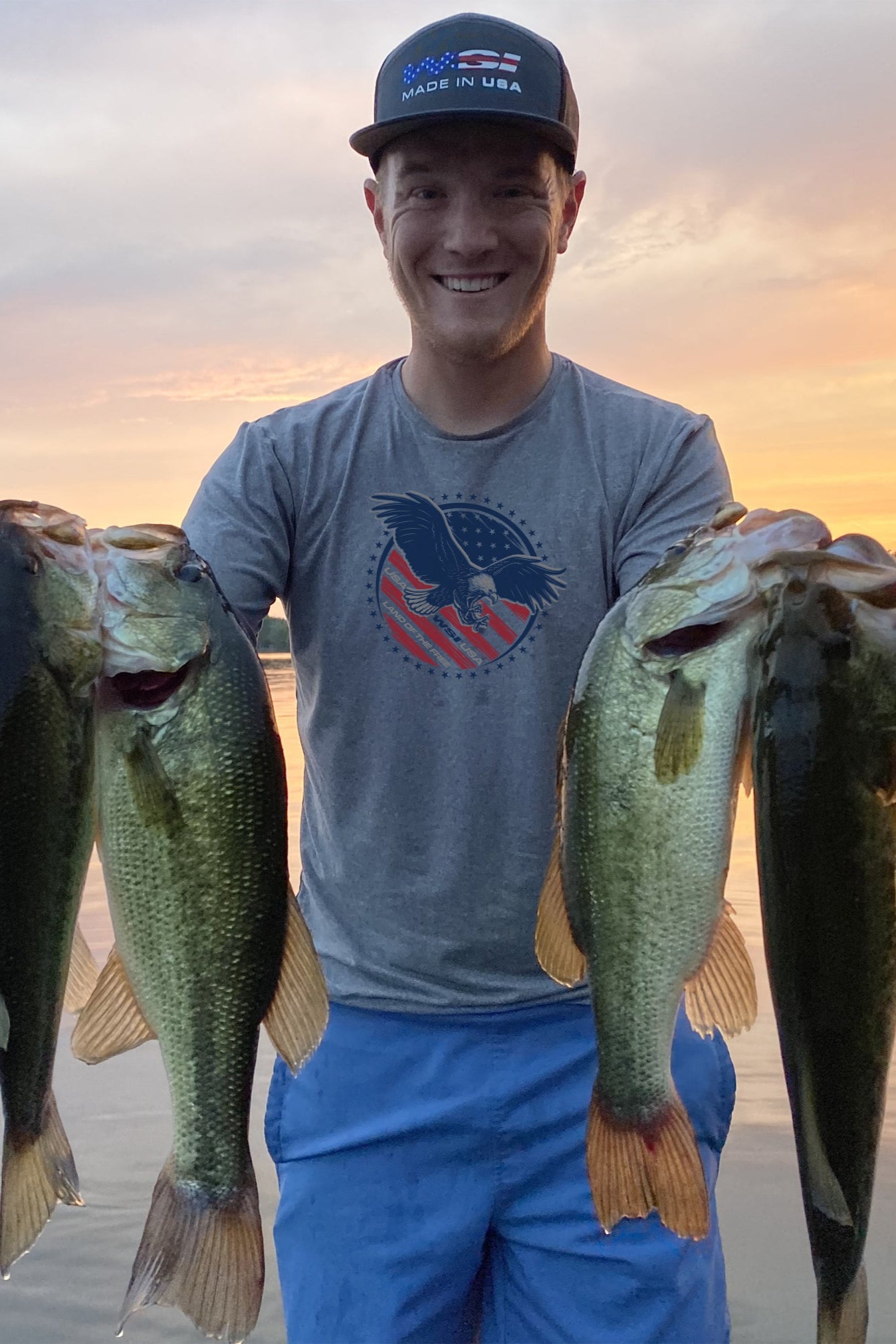 Man holding fish while wearing a WSI Sports Heather Grey Mens T-shirt with Red and Blue Eagle Print