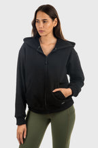 Woman wearing a black hoodie and green pants on a white background