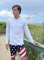 Man wearing white textured hoodie and USA shorts on the beach
