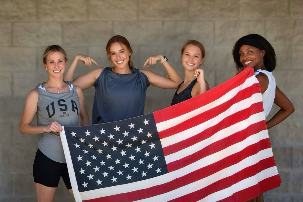 Four women holding an American flag against a brick wall while wearing activloops sports bras